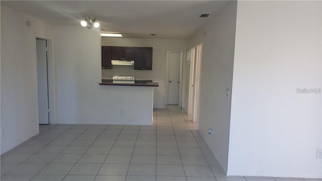 empty room with dark brown cabinets and light tile patterned flooring