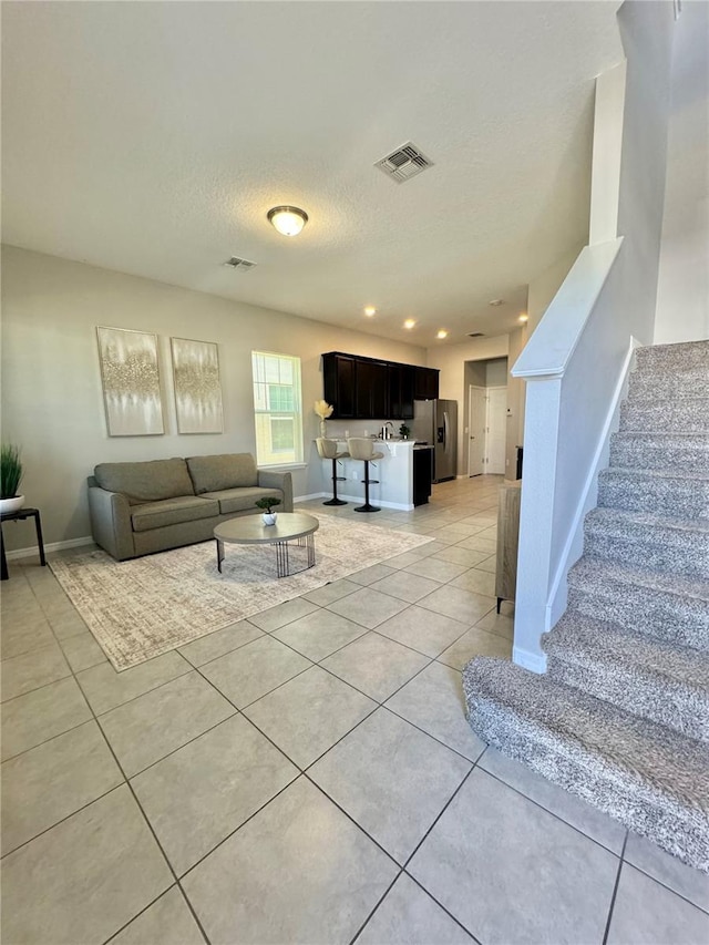 living room featuring sink, light tile patterned floors, and a textured ceiling