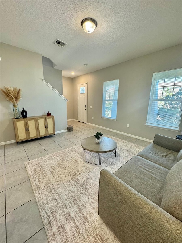 living room featuring light tile patterned flooring, plenty of natural light, and a textured ceiling