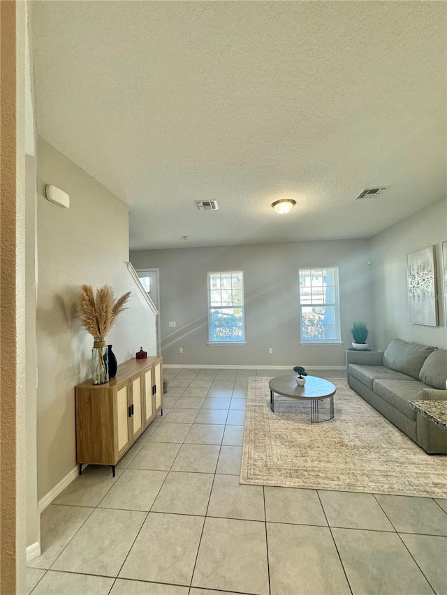 tiled living room featuring a textured ceiling