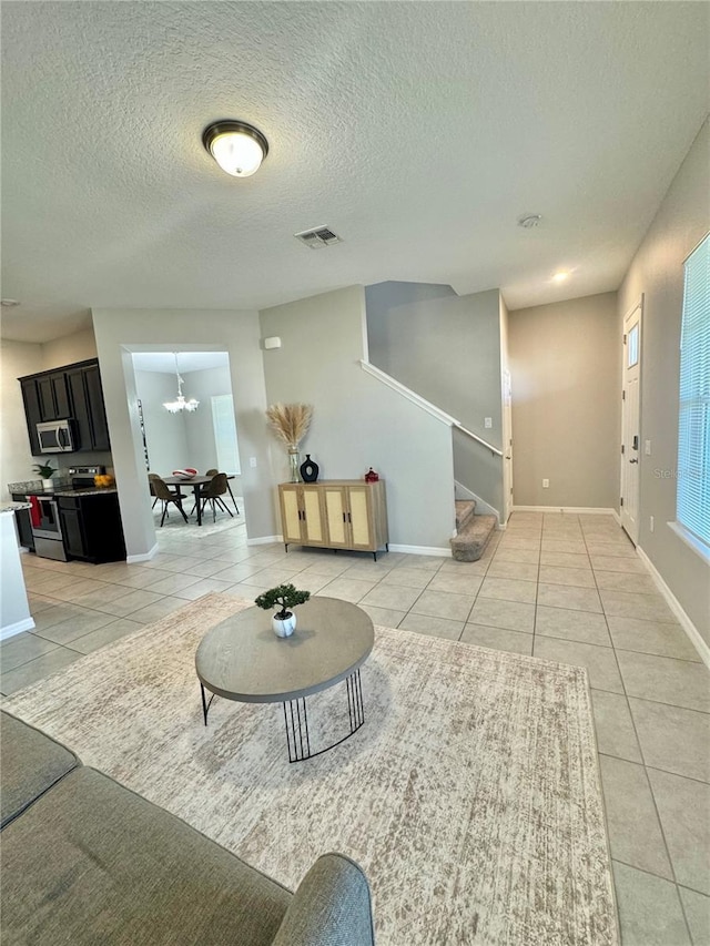 interior space featuring a textured ceiling, tile patterned floors, and an inviting chandelier