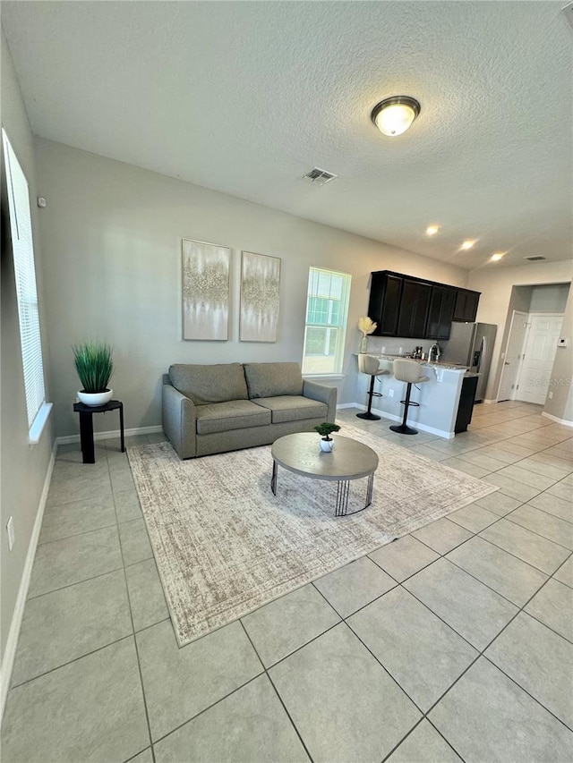 living room with a textured ceiling and light tile patterned floors