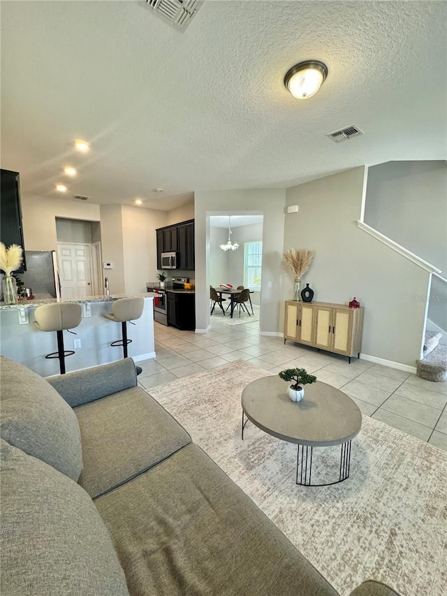 living room featuring light tile patterned flooring, an inviting chandelier, and a textured ceiling