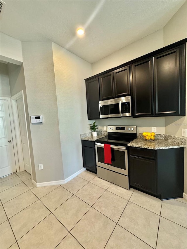 kitchen with light stone counters, appliances with stainless steel finishes, and light tile patterned flooring