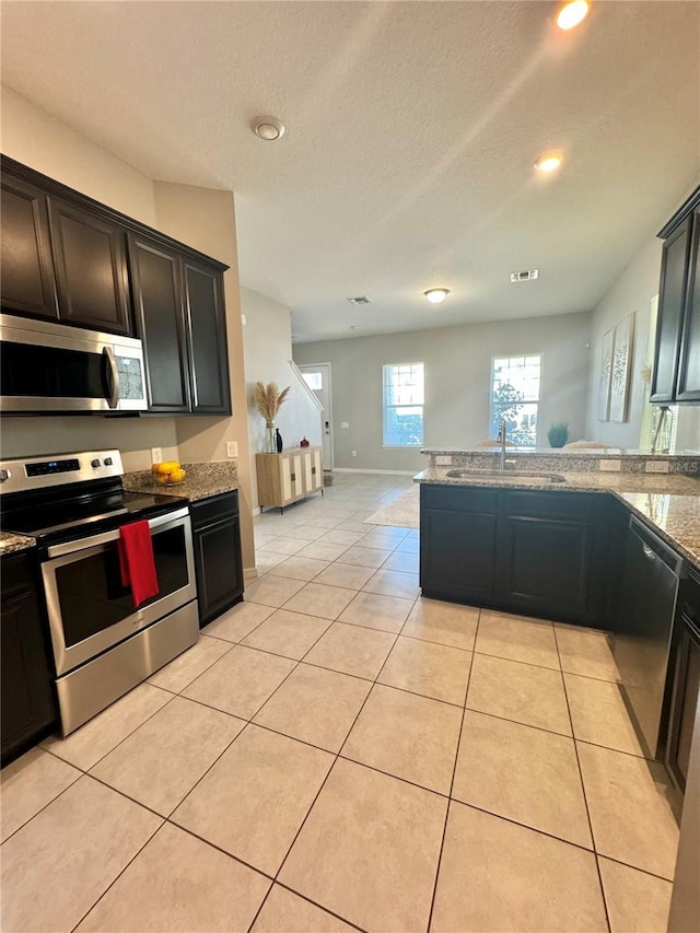 kitchen with light stone counters, sink, light tile patterned floors, and appliances with stainless steel finishes