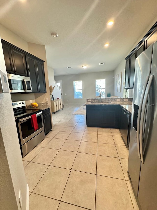 kitchen featuring appliances with stainless steel finishes, sink, light tile patterned floors, and kitchen peninsula