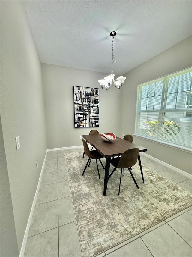 tiled dining room featuring an inviting chandelier and a textured ceiling