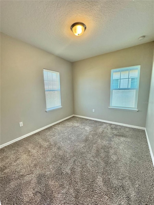 carpeted spare room featuring a textured ceiling