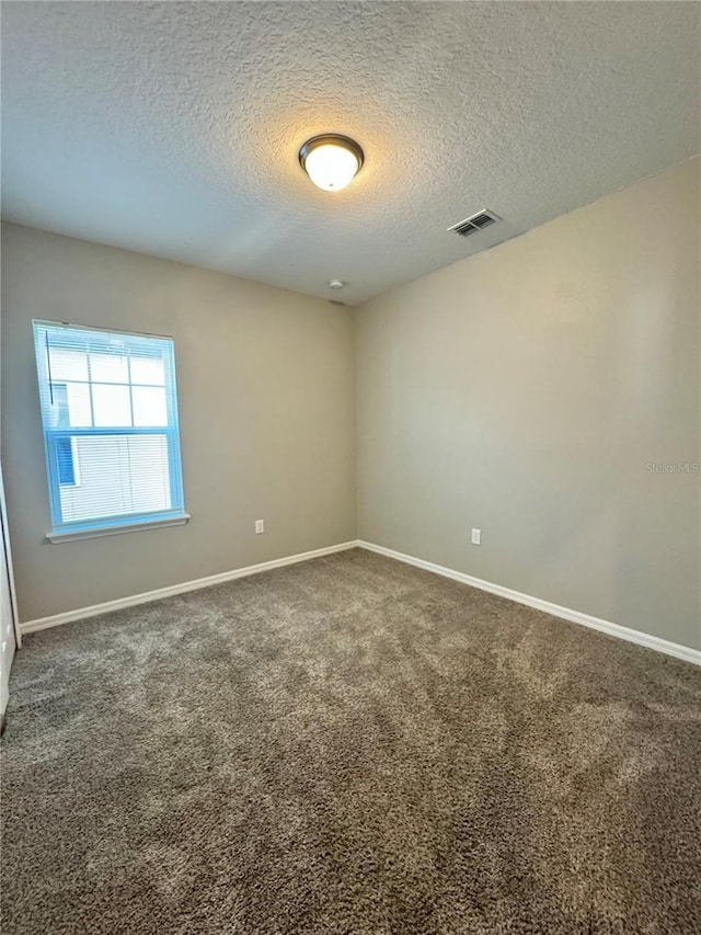 carpeted empty room featuring a textured ceiling