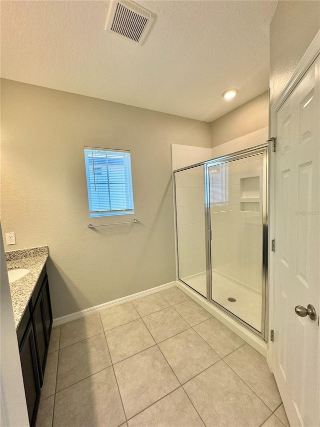 bathroom featuring a shower with door, vanity, tile patterned floors, and a textured ceiling