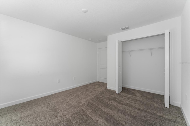 unfurnished bedroom featuring dark colored carpet and a closet