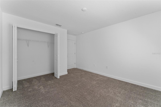 unfurnished bedroom featuring dark carpet and a closet