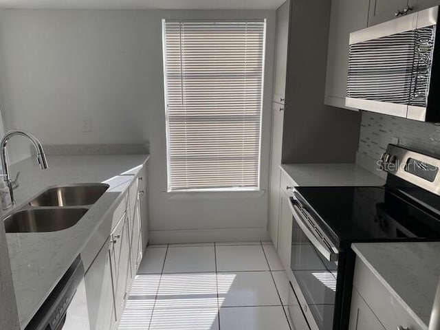 kitchen with sink, tasteful backsplash, light tile patterned floors, appliances with stainless steel finishes, and white cabinets