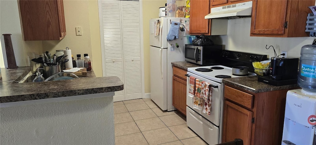 kitchen with electric range oven, light tile patterned floors, and white refrigerator