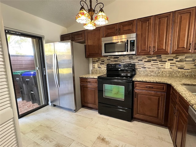 kitchen with lofted ceiling, hanging light fixtures, backsplash, and appliances with stainless steel finishes