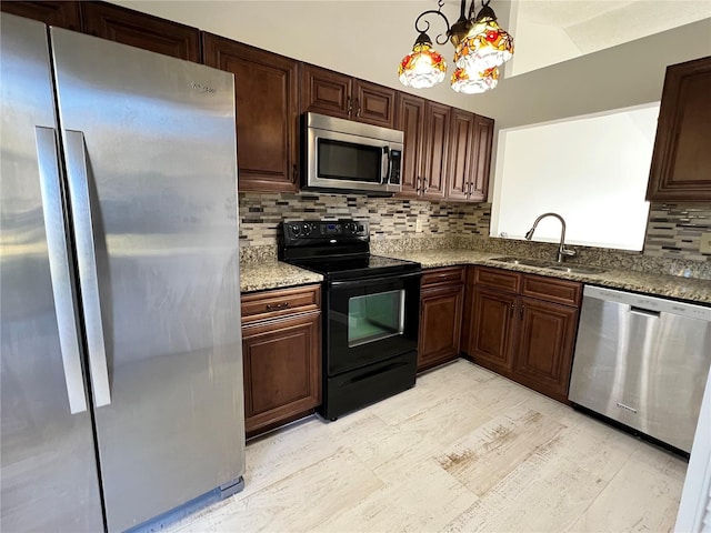 kitchen with pendant lighting, sink, light stone countertops, and appliances with stainless steel finishes