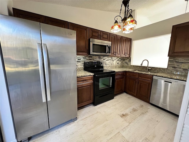 kitchen featuring sink, light stone counters, vaulted ceiling, hanging light fixtures, and stainless steel appliances