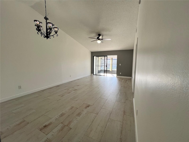 empty room featuring lofted ceiling, light hardwood / wood-style floors, ceiling fan with notable chandelier, and a textured ceiling