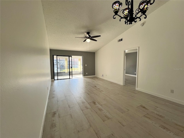 empty room featuring lofted ceiling, a textured ceiling, light hardwood / wood-style flooring, and ceiling fan