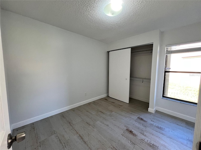 unfurnished bedroom with light wood-type flooring, a closet, and a textured ceiling