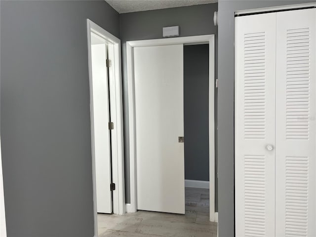 hall featuring light hardwood / wood-style flooring and a textured ceiling