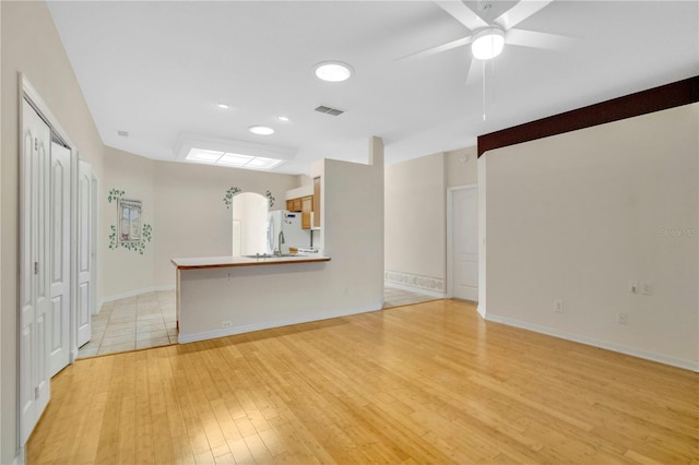 unfurnished living room featuring ceiling fan and light hardwood / wood-style floors