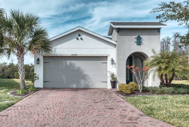 view of front facade with an attached garage, decorative driveway, and stucco siding