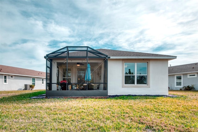 rear view of property with a lawn and glass enclosure