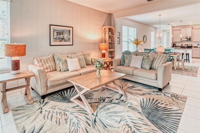 tiled living room with a notable chandelier