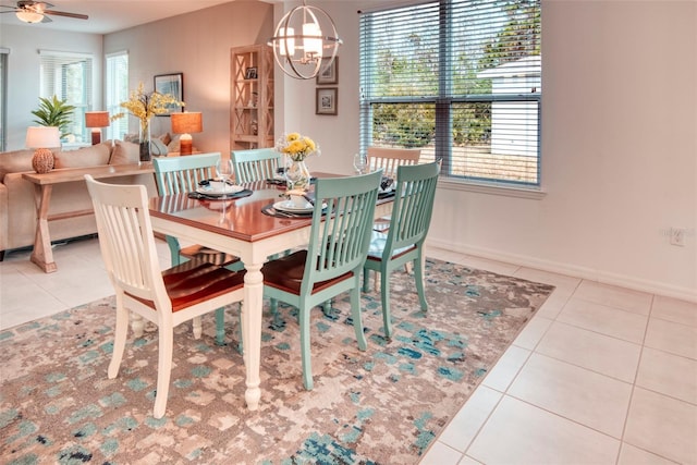 tiled dining room featuring ceiling fan with notable chandelier