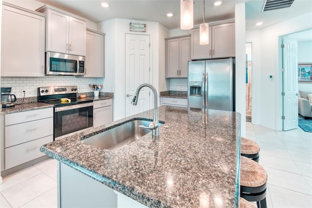 kitchen with sink, stainless steel appliances, a kitchen breakfast bar, and an island with sink