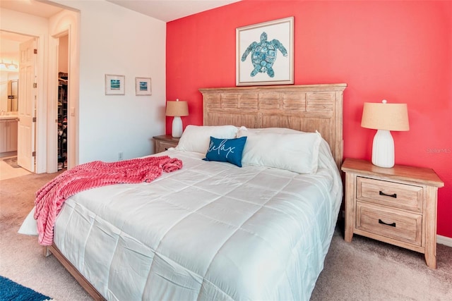 bedroom with ensuite bathroom and light carpet