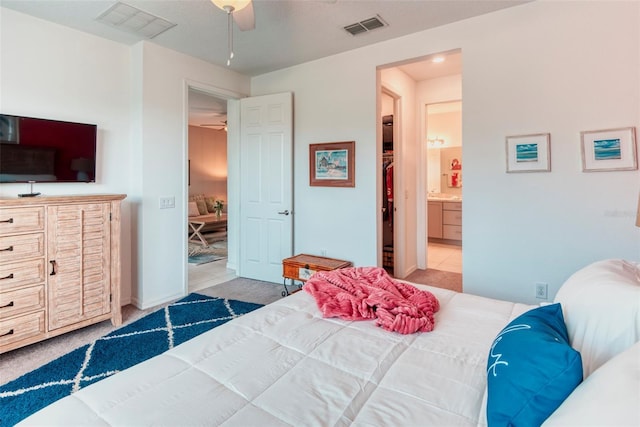 bedroom with connected bathroom, light carpet, and ceiling fan