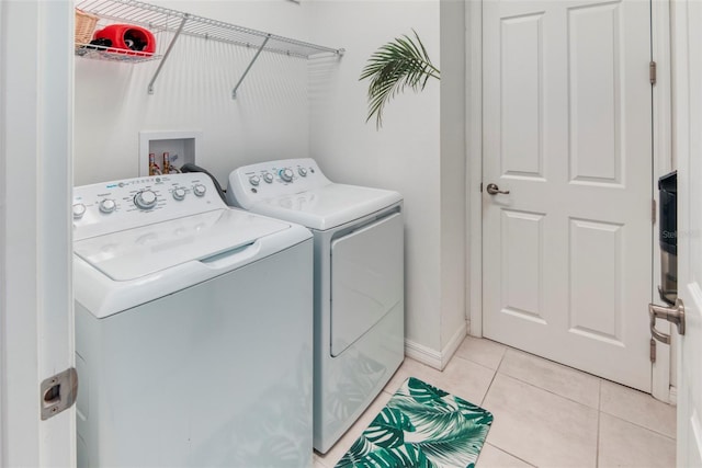 clothes washing area featuring light tile patterned floors and independent washer and dryer