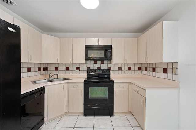 kitchen with tasteful backsplash, sink, light tile patterned floors, and black appliances