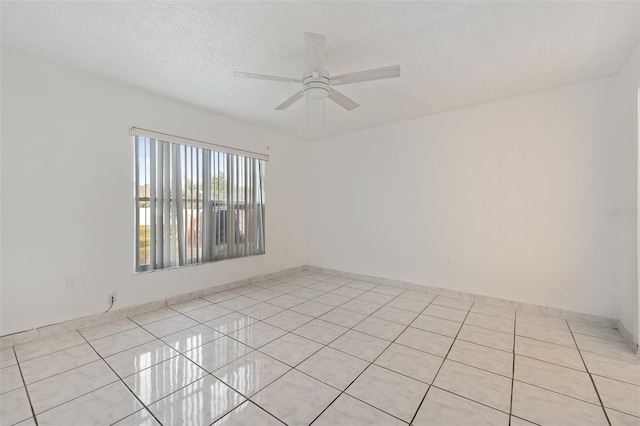 tiled empty room featuring ceiling fan and a textured ceiling