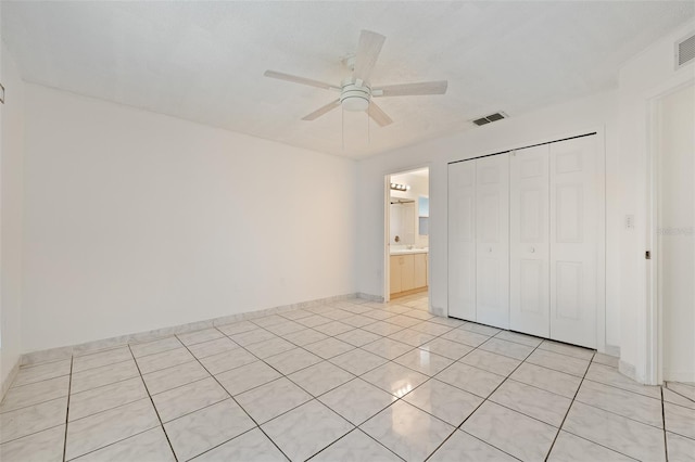 unfurnished bedroom with ceiling fan, connected bathroom, a closet, and light tile patterned floors