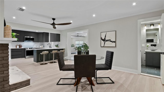 dining space with ornamental molding, sink, ceiling fan, and light wood-type flooring