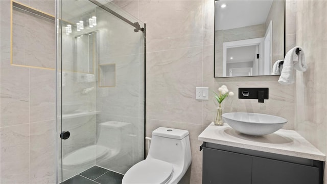 bathroom featuring a shower with door, tile walls, vanity, tile patterned floors, and toilet