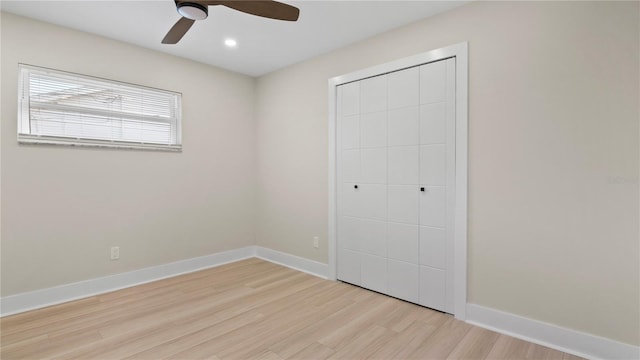 unfurnished bedroom with light wood-type flooring, ceiling fan, and a closet