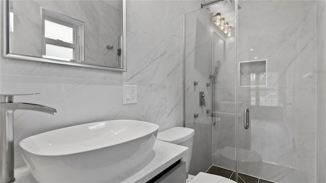 bathroom with an enclosed shower, vanity, tile walls, and toilet