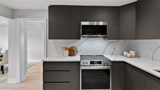 kitchen featuring decorative backsplash, light hardwood / wood-style flooring, and stainless steel appliances