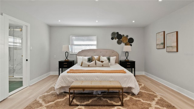 bedroom featuring connected bathroom and light hardwood / wood-style flooring