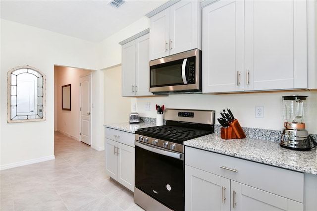 kitchen with white cabinetry, light stone countertops, appliances with stainless steel finishes, and light tile patterned floors