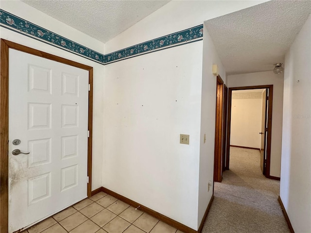 entryway with light tile patterned flooring and a textured ceiling