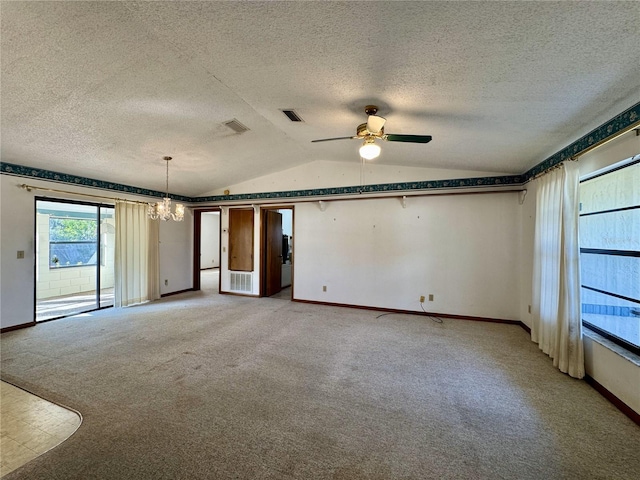 carpeted empty room featuring lofted ceiling, ceiling fan with notable chandelier, and a textured ceiling