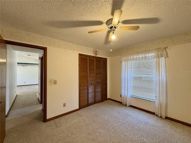 unfurnished bedroom with ceiling fan, light carpet, a closet, and a textured ceiling