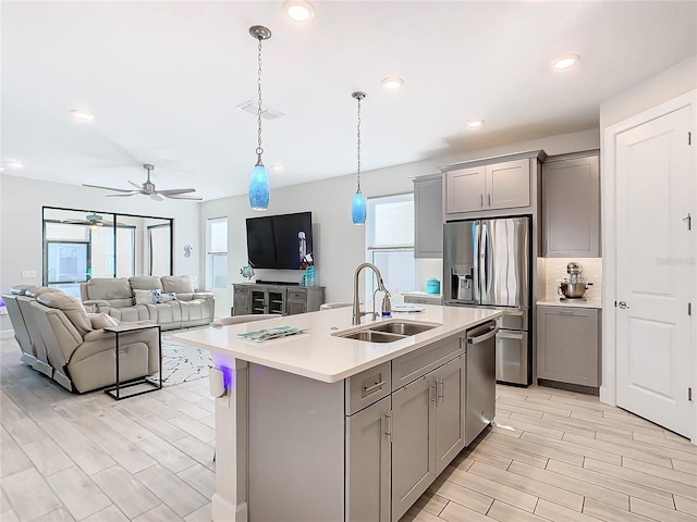 kitchen featuring pendant lighting, sink, an island with sink, and gray cabinetry