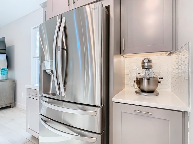 kitchen with stainless steel fridge, gray cabinets, and decorative backsplash