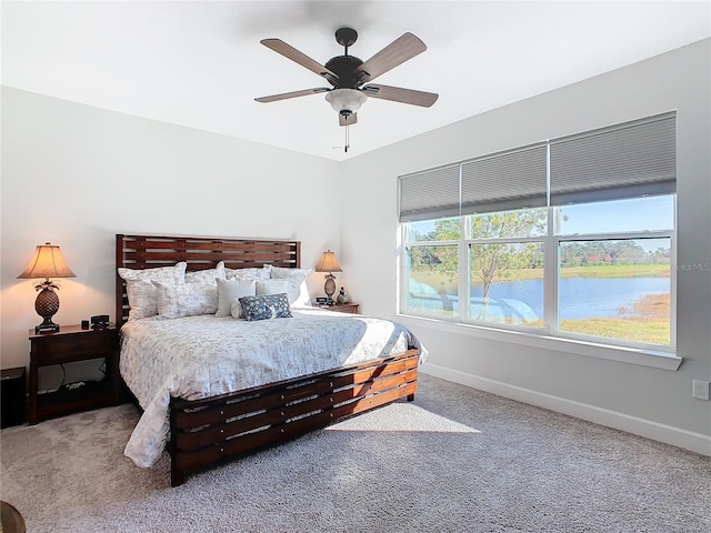 carpeted bedroom with ceiling fan and a water view